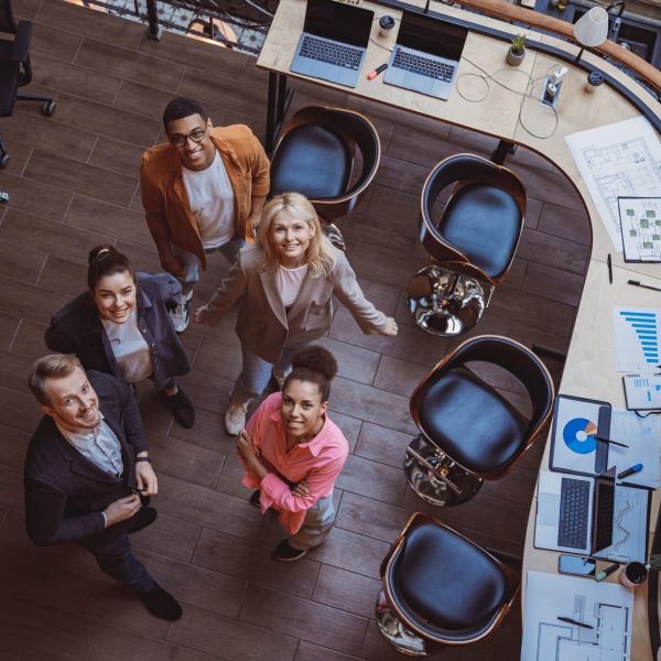 Group of coworkers working together while standing at modern office. Unity concept