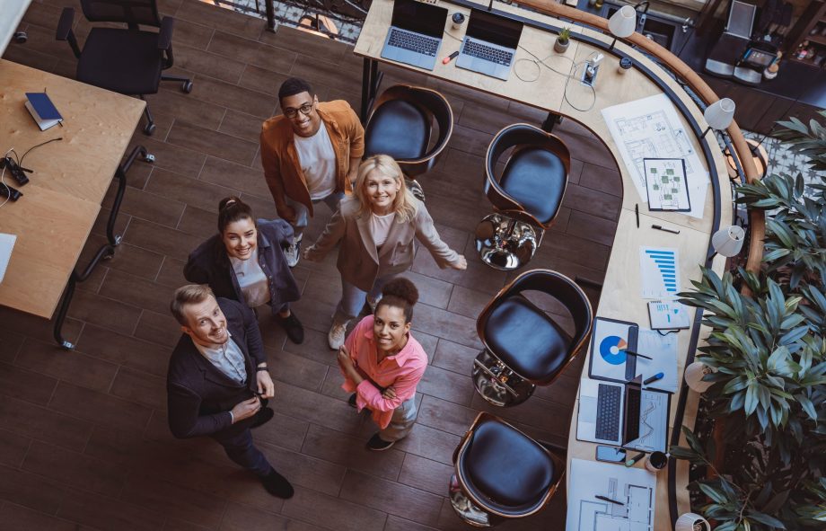 Group of coworkers working together while standing at modern office. Unity concept