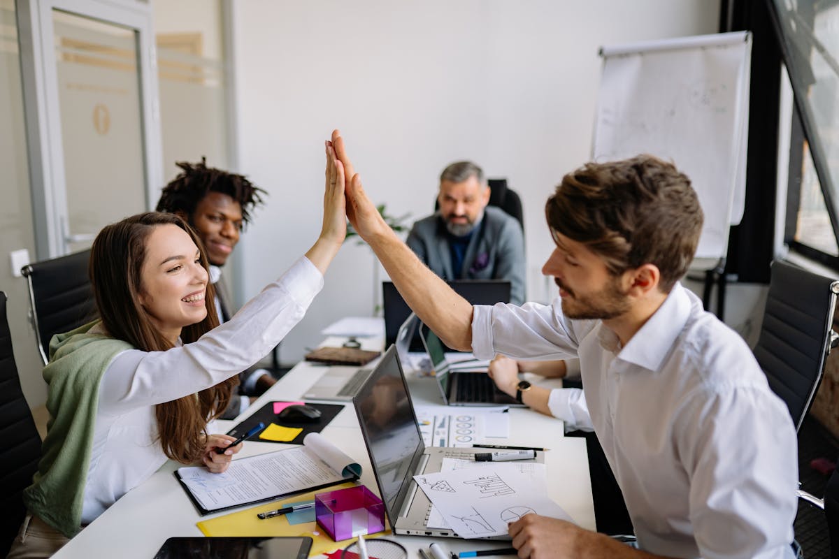 Team high-fiving during a brand strategy session, illustrating how strong brand culture builds trust, alignment, and consistent customer experience beyond short-term pop culture trends.
