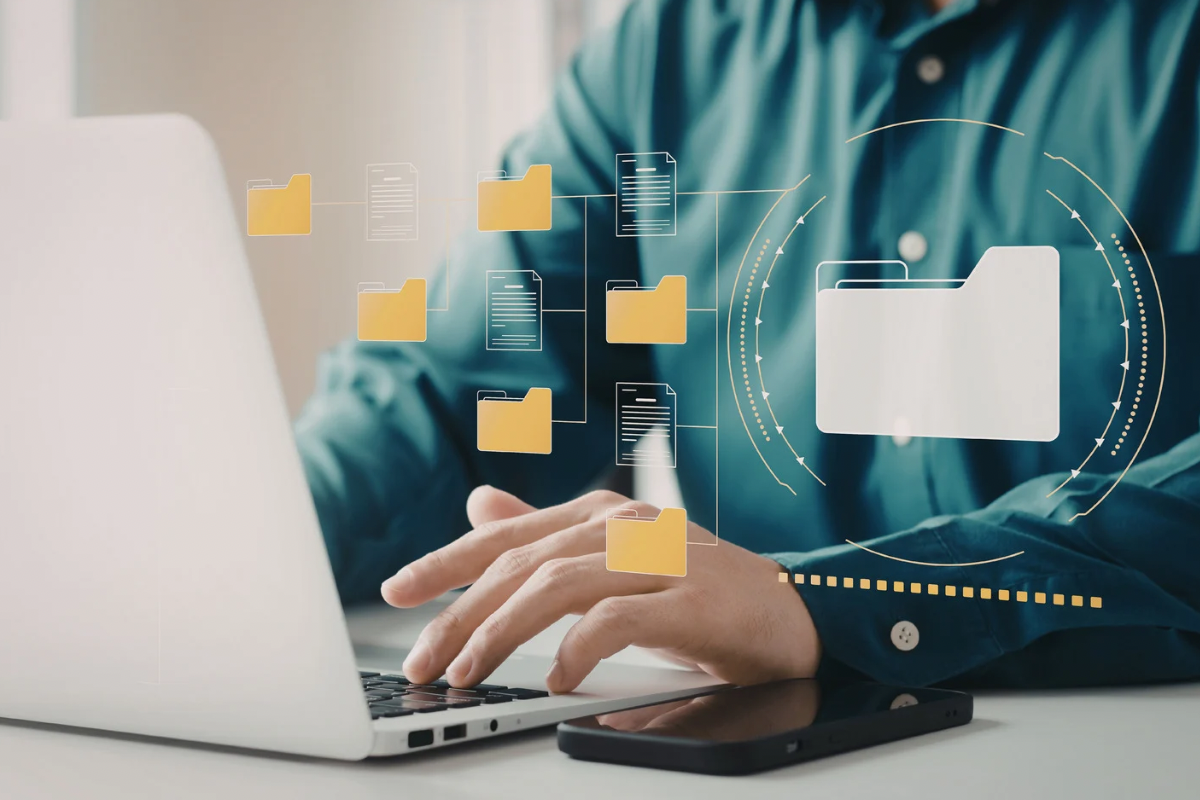 Person working on a laptop with digital folders and interface components overlayed, representing a scalable digital brand system.