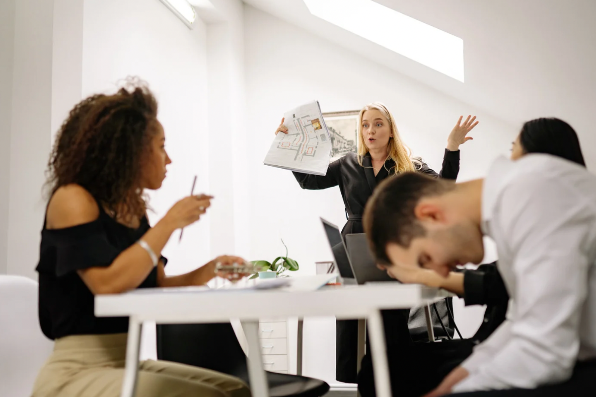 Tense team meeting scene showing internal pressure and employee cognitive dissonance.
