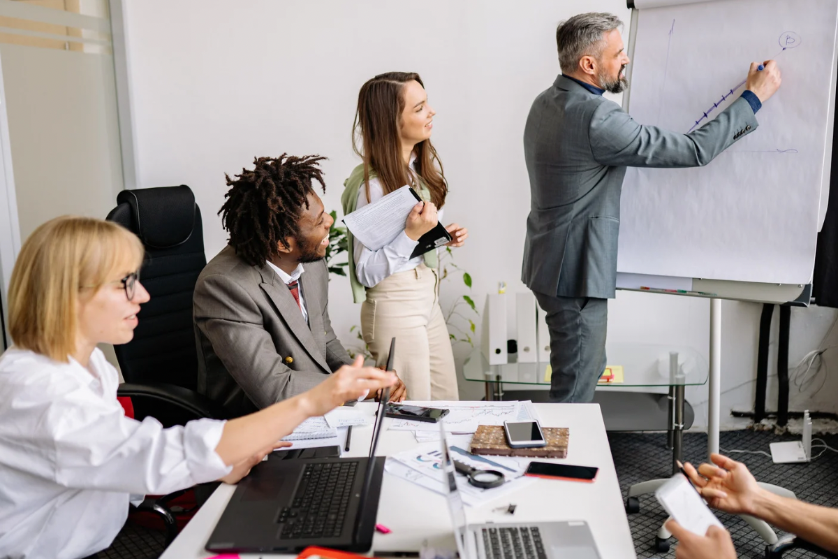 A marketing team during a strategy workshop at a whiteboard, mapping out the trade-offs required to make a brand’s positioning stick.