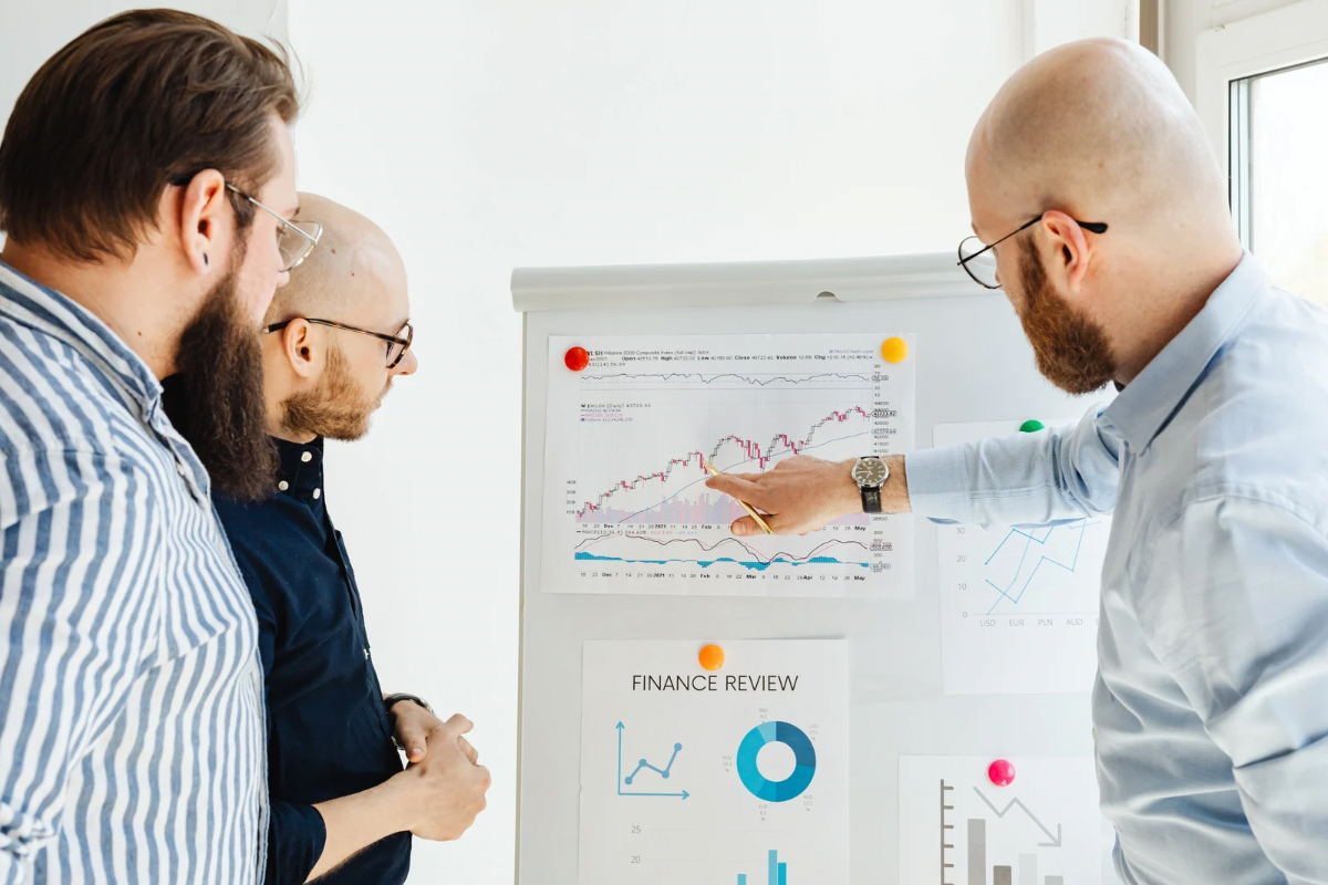 Two professionals analyzing financial charts and customer data on a whiteboard to predict purchase behavior.