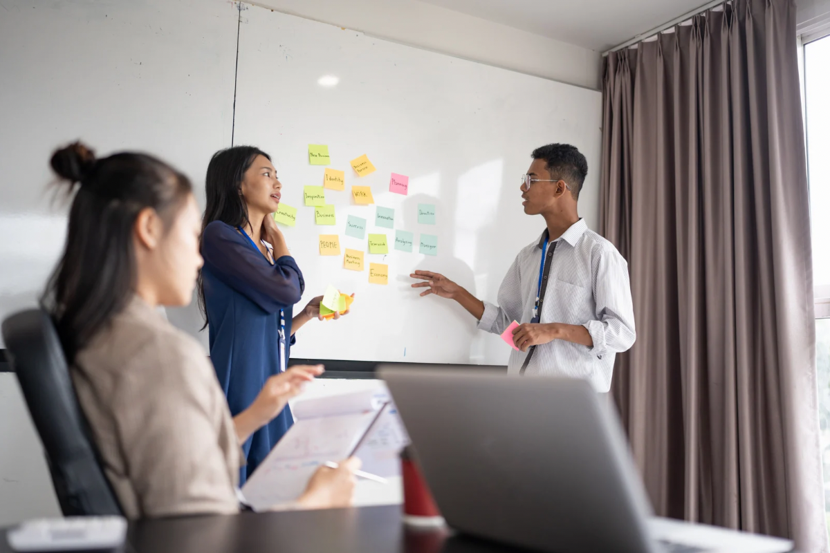 Business team collaborating at a whiteboard to document company culture and brand narratives.